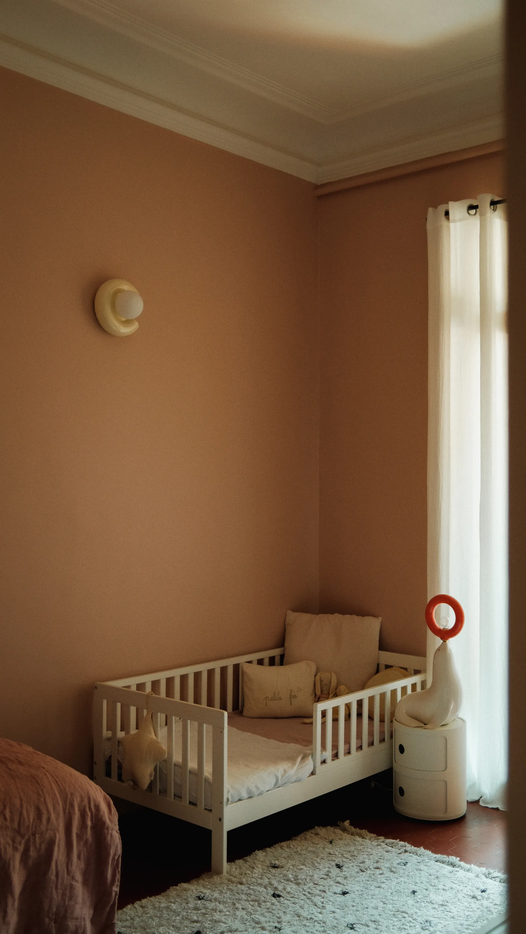 Chambre enfant — murs terre, applique vintage, tapis berbère