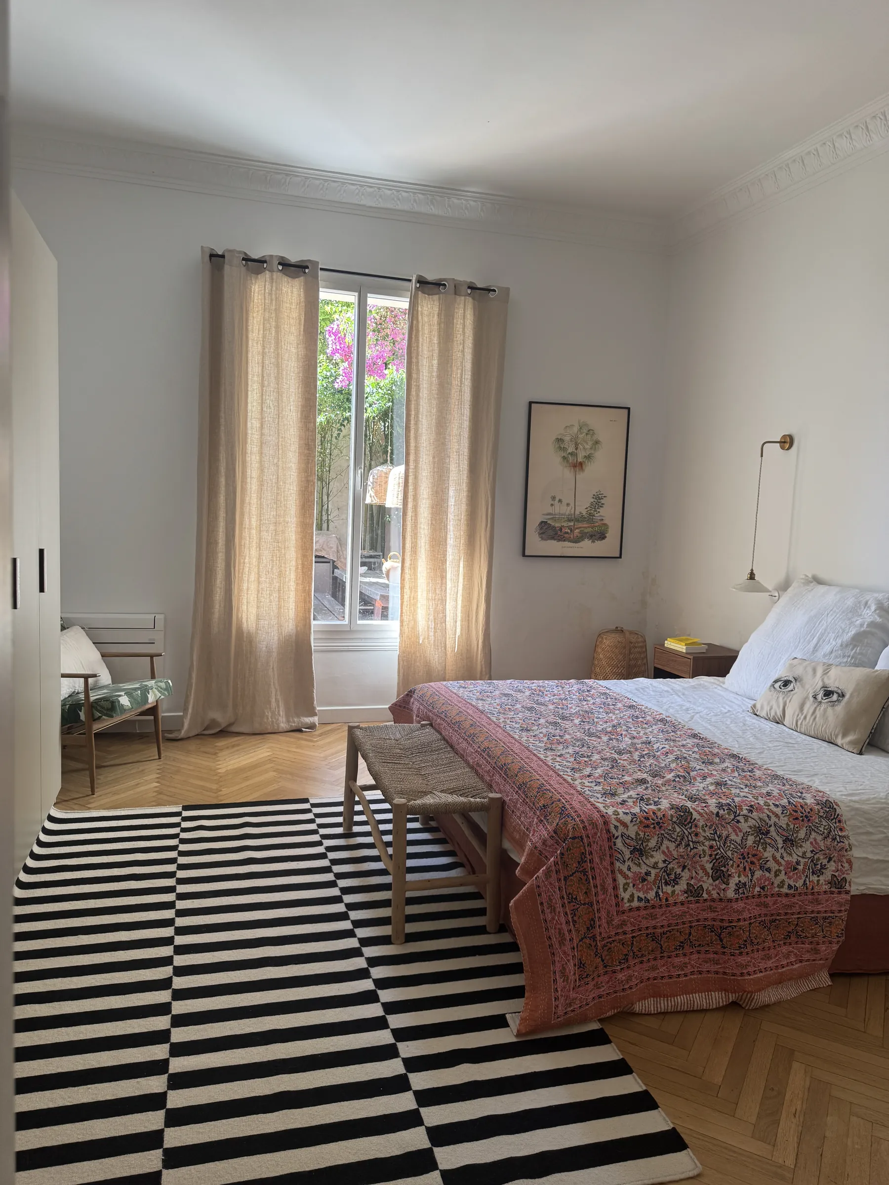 Chambre principale — couvre-lit floral et tapis rayé