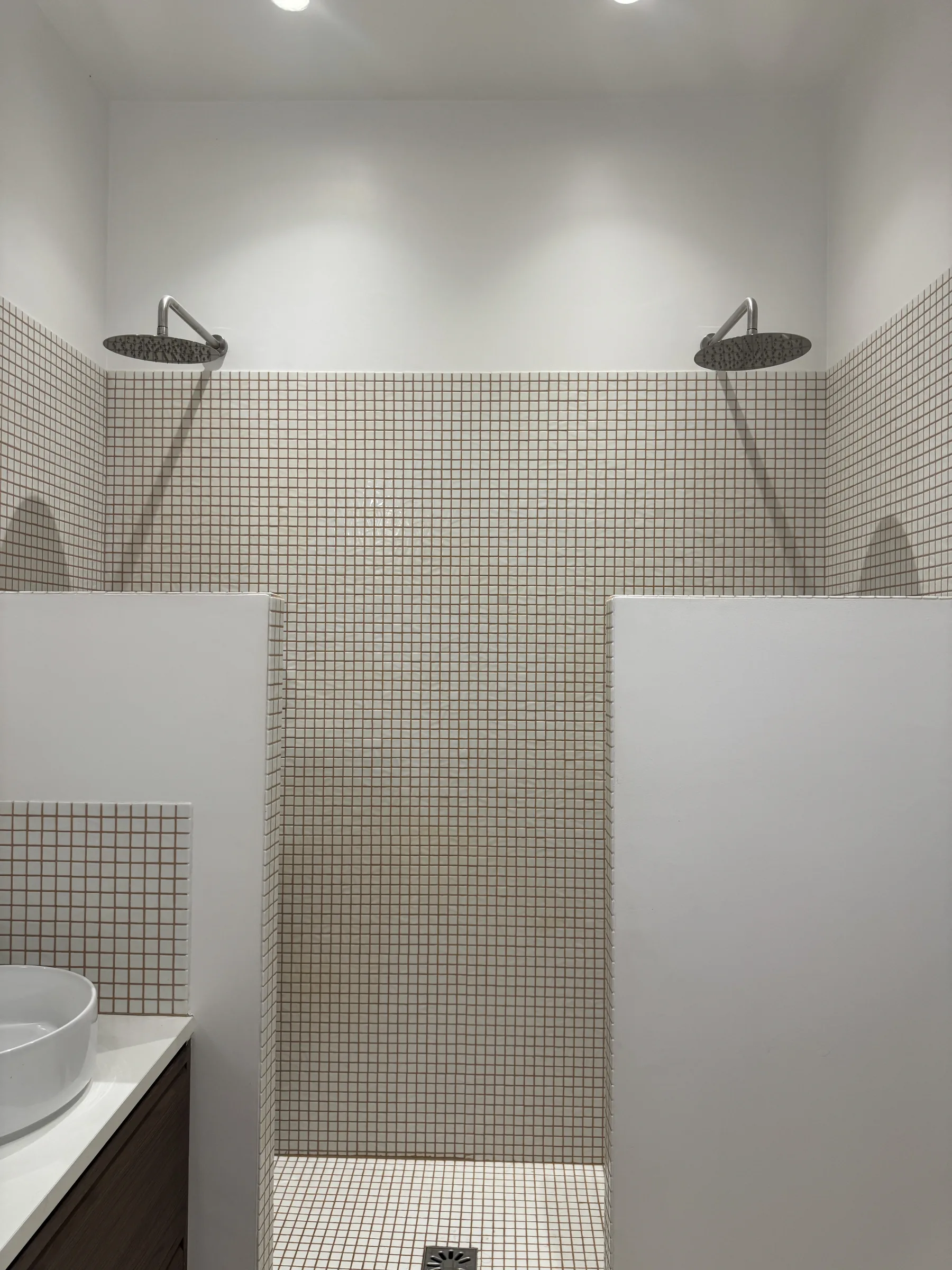 Double douche — deux pommeaux face à face, faïence blanche à joints terra